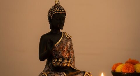 Meditating Buddha statue tealight candle holder with lit candle on wooden meditation table